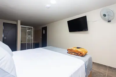 a bedroom with a white bed and a flat screen tv at Hotel Bossanova in Rionegro
