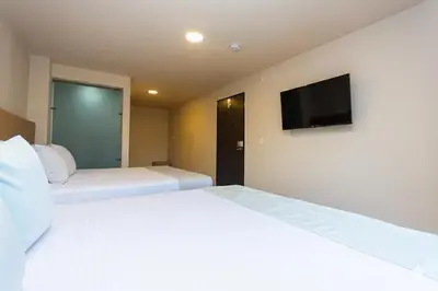 a bedroom with two beds and a flat screen tv at Hotel Bossanova in Rionegro