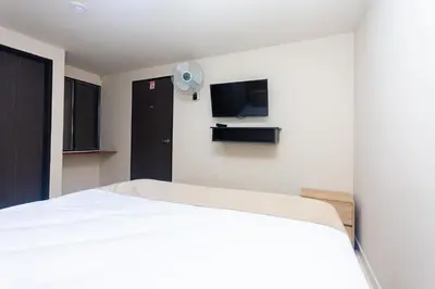 a bedroom with a white bed and a flat screen tv at Hotel Bossanova in Rionegro