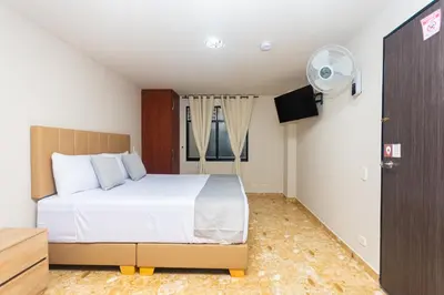 a bedroom with a white bed and a fan at Hotel Bossanova in Rionegro
