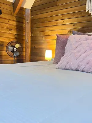 a bedroom with a bed with a fan and wooden walls at Qimera Ecolodge - Cabaña a 7 Min del Aeropuerto JMC in Guarne