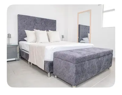 a bedroom with a large bed and a ottoman at Apartahotel Ginebra central cerca laureles in Medellín