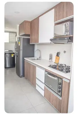 a kitchen with wooden cabinets and a stainless steel refrigerator at Apartahotel Ginebra central cerca laureles in Medellín