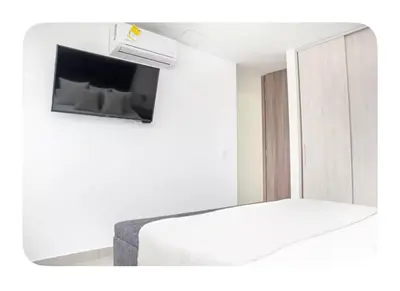a room with a bed and a tv on a wall at Apartahotel Ginebra central cerca laureles in Medellín