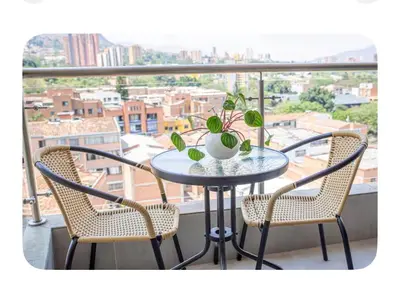 a table and chairs on a balcony with a view at Apartahotel Ginebra central cerca laureles in Medellín