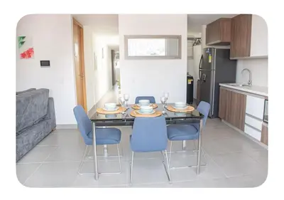 a kitchen with a dining room table with blue chairs at Apartahotel Ginebra central cerca laureles in Medellín
