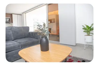 a vase with flowers on a table in a living room at Apartahotel Ginebra central cerca laureles in Medellín
