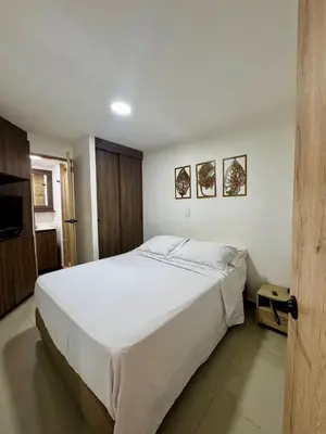 a bedroom with a large white bed and a television at Apartamento Blanco in Medellín