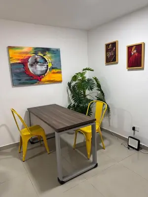 a dining room with a table and two yellow chairs at Apartamento Blanco in Medellín