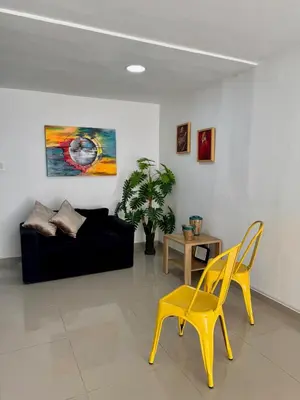 a living room with a black couch and a yellow chair at Apartamento Blanco in Medellín