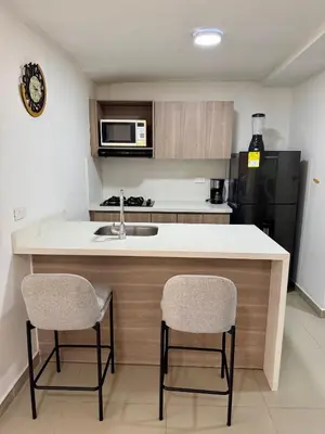 a kitchen with a sink and a counter with two chairs at Apartamento Blanco in Medellín
