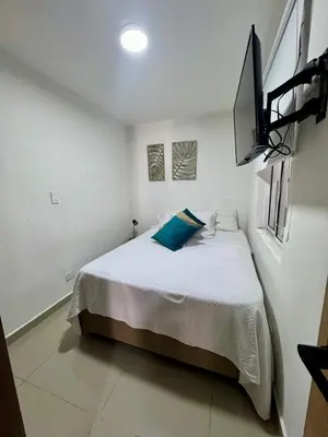 a white bedroom with a bed with a blue pillow at Apartamento Blanco in Medellín