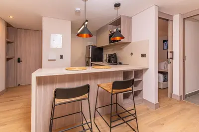 a kitchen with a counter and two stools at Jatisa Living by Housy in Medellín