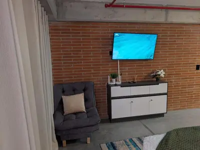 a room with a chair and a tv on a brick wall at Baseloft in Medellín