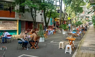 a group of people sitting at tables on a city street at One Apartments Provenza in Medellín