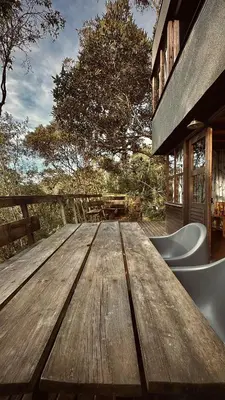 a wooden table in front of a house at Lodge Kumbre Santa Elena Bosque Privado in Medellín