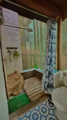 a bathroom with a shower with a toilet and a rock at Lodge Kumbre Santa Elena Bosque Privado in Medellín