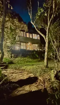 a house in the middle of a forest at night at Lodge Kumbre Santa Elena Bosque Privado in Medellín