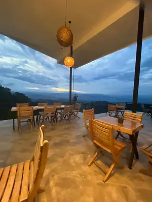 a group of wooden tables and chairs on a patio at ZOI Eco Hotel y Glamping in Manizales