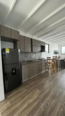 a kitchen with a black refrigerator and wooden cabinets at ZOI Eco Hotel y Glamping in Manizales