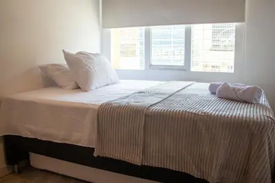 a bed with white sheets and pillows in a bedroom at 2 Cuadras Estadio - La 70, Laureles, 700MB, AC in Medellín