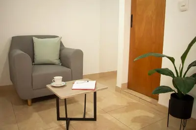 a living room with a chair and a coffee table at 2 Cuadras Estadio - La 70, Laureles, 700MB, AC in Medellín