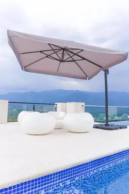 a white umbrella sitting on the edge of a swimming pool at Finca golden house en santa fe de antioquia in El Espinal