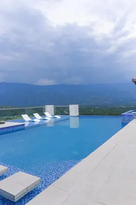a swimming pool with white lounge chairs on a building at Finca golden house en santa fe de antioquia in El Espinal