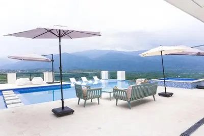 a pool with a table and chairs and umbrellas at Finca golden house en santa fe de antioquia in El Espinal