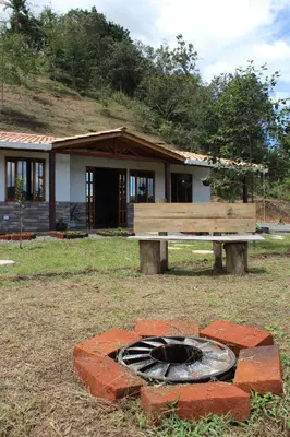 a bench and a fire pit in front of a house at Alma Casa Finca in Guarne
