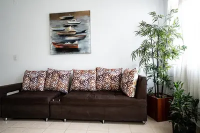 a brown couch in a living room with two plants at La Esquinita de Miraflores in Medellín
