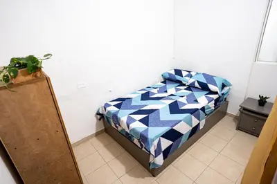 a bedroom with a bed with a blue and white quilt at La Esquinita de Miraflores in Medellín