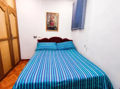 a bed with a blue and white striped comforter in a room at Casa de Confort con Parqueadero Privado in Medellín