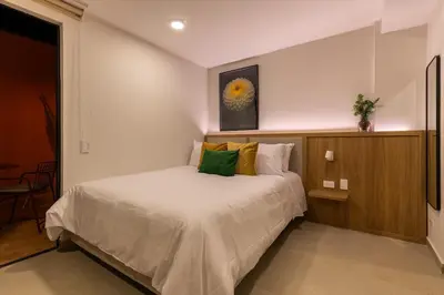 a bedroom with a white bed with green pillows at 201 Stylish Retreat in Laureles Area Terrace AC in Medellín