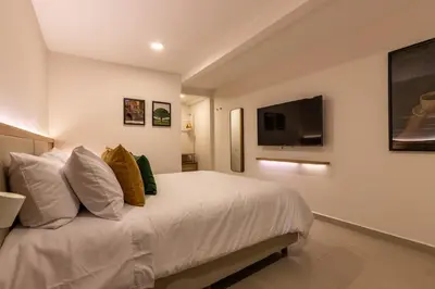 a bedroom with a white bed and a flat screen tv at 202 Modern Stay in Laureles Area Cozy Balcony AC in Medellín