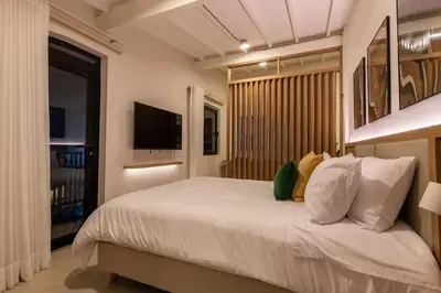 a bedroom with a bed with white sheets and a television at 301 Live Local Balcony Loft in Vibrant Laureles area in Medellín