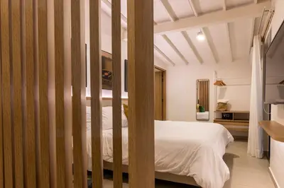 a bedroom with a white bed with wooden posts at 301 Live Local Balcony Loft in Vibrant Laureles area in Medellín