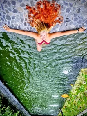 a woman laying in the water with her arms out at Madremonte Santa Elena finca con cabaña para 2 con piscina natural in Medellín