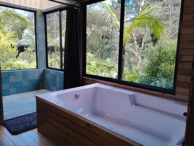 a bath tub in a bathroom with windows at Madremonte Santa Elena finca con cabaña para 2 con piscina natural in Medellín
