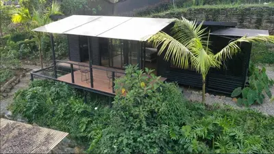 a small black house with a white roof at Madremonte Santa Elena finca con cabaña para 2 con piscina natural in Medellín