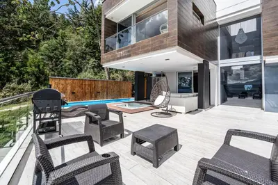 a patio with chairs and a pool in a house at Mansión en las palmas Pool ,Jacuzzi,View in Medellín