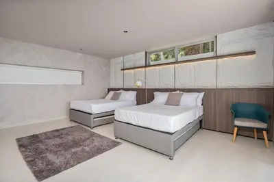a bedroom with two beds and a chair at Mansión en las palmas Pool ,Jacuzzi,View in Medellín