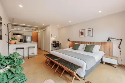 a bedroom with a large bed and a kitchen at Loft comodo y central con AC y Terraza propia en Astorga Poblado in Medellín