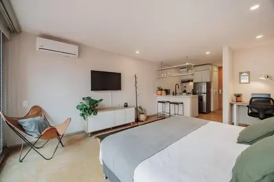 a bedroom with a large bed and a kitchen at Loft comodo y central con AC y Terraza propia en Astorga Poblado in Medellín