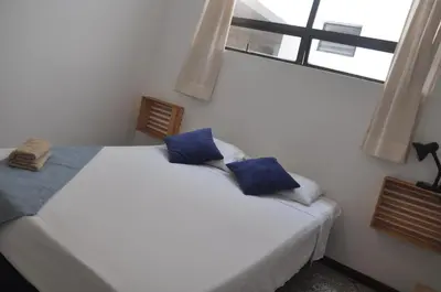 a bedroom with a bed with blue pillows and a window at Laureles, casa completa y amplia para grupos grandes in Medellín