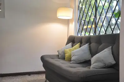 a couch with pillows on it in front of a window at Laureles, casa completa y amplia para grupos grandes in Medellín