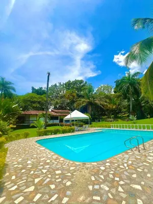 a swimming pool in front of a house with palm trees at Finca - Paraiso in Medellín
