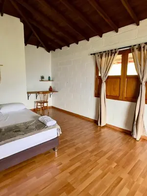 a bedroom with a bed and a wooden floor at Entre Cafetales in Jardin