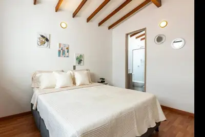 a white bedroom with a large bed with white sheets at Lujoso pent-house de dos niveles in Itagüí