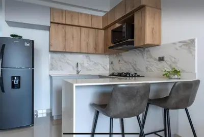 a kitchen with a counter with two chairs and a refrigerator at Lujoso pent-house de dos niveles in Itagüí